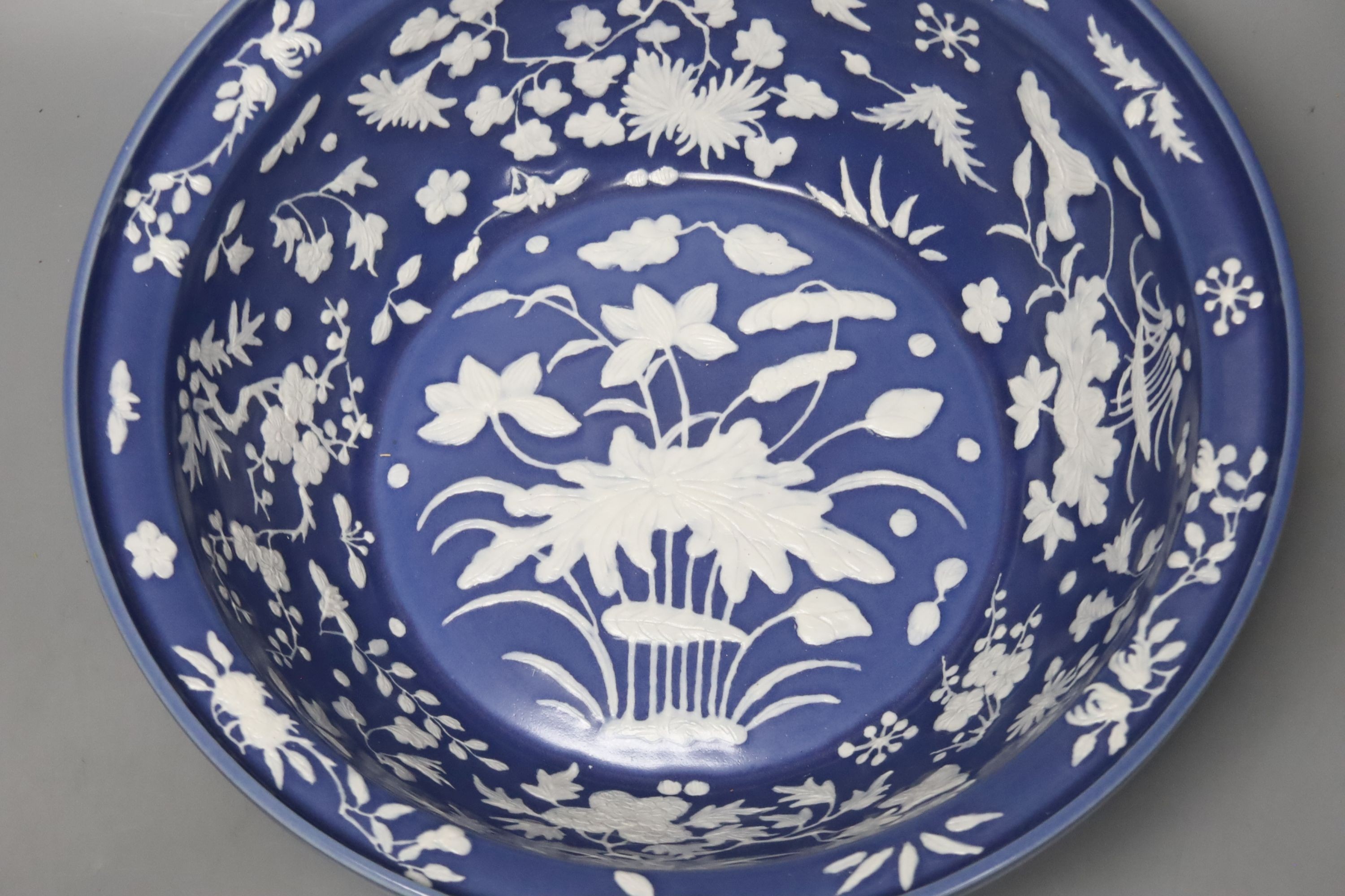 A large Chinese blue and white porcelain basin, lightly relief moulded with plants, 40cm